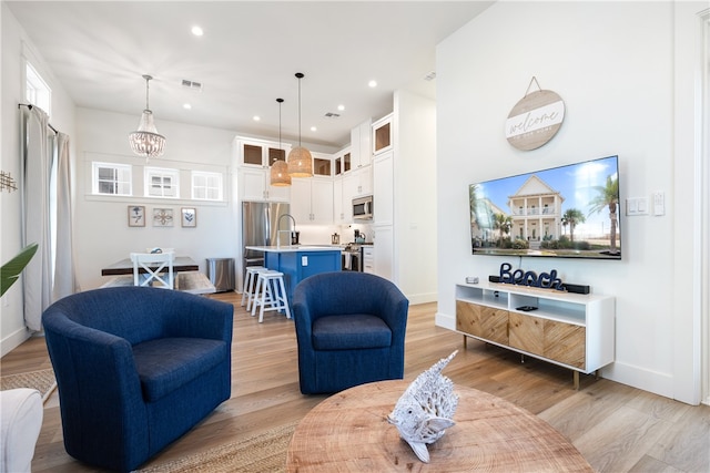 living room featuring light hardwood / wood-style floors and an inviting chandelier