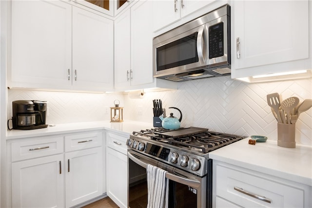 kitchen with white cabinets, appliances with stainless steel finishes, and backsplash