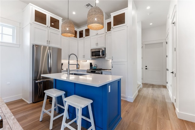 kitchen with a kitchen island with sink, sink, light hardwood / wood-style flooring, and appliances with stainless steel finishes