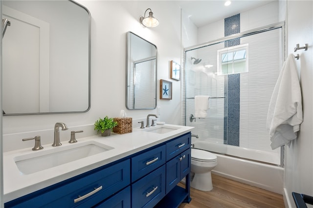 full bathroom with shower / bath combination with glass door, toilet, vanity, and hardwood / wood-style flooring