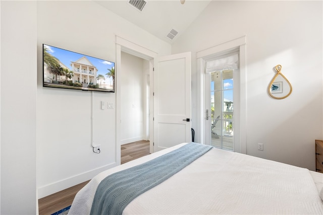 bedroom featuring access to exterior, vaulted ceiling, and hardwood / wood-style flooring