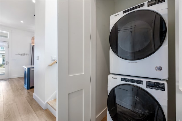 clothes washing area featuring stacked washer / dryer and light wood-type flooring