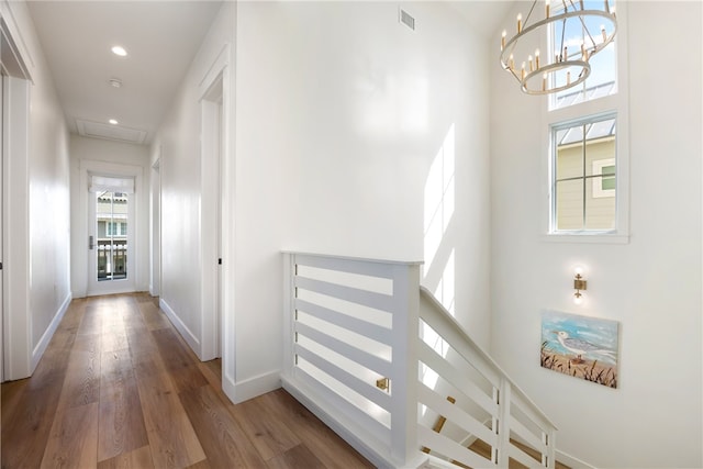 hall with hardwood / wood-style floors, a notable chandelier, and a high ceiling