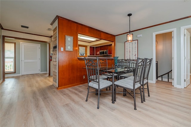 dining room with light hardwood / wood-style floors and ornamental molding