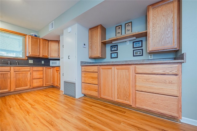 kitchen with sink, decorative backsplash, and light hardwood / wood-style floors