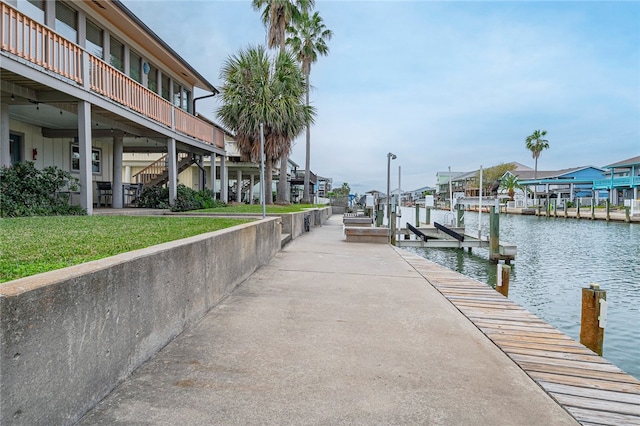 view of dock with a water view and a lawn