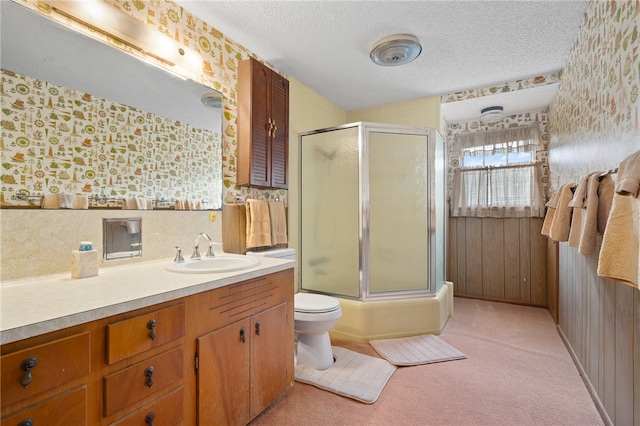 full bathroom with toilet, wooden walls, a textured ceiling, shower / bath combination with glass door, and vanity