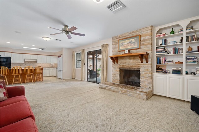 carpeted living room featuring a fireplace and ceiling fan