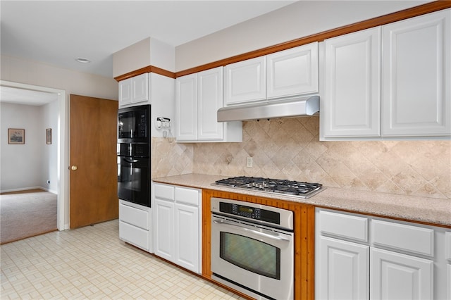 kitchen with white cabinets, appliances with stainless steel finishes, backsplash, and light stone countertops