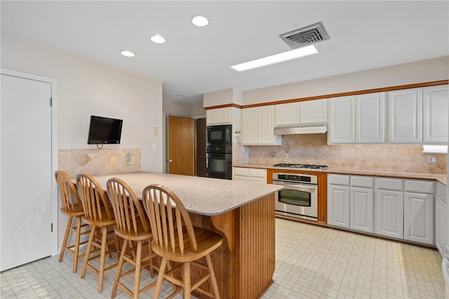 kitchen featuring white cabinets, a breakfast bar area, black appliances, and kitchen peninsula