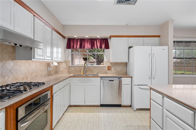 kitchen with sink, appliances with stainless steel finishes, backsplash, white cabinets, and exhaust hood