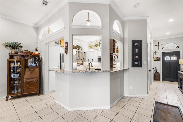 kitchen featuring kitchen peninsula, light stone counters, stainless steel appliances, white cabinets, and light tile patterned flooring