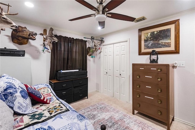 bedroom featuring ceiling fan, a closet, crown molding, and light carpet