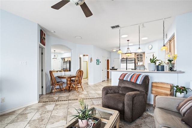 living area with arched walkways, visible vents, baseboards, a ceiling fan, and rail lighting