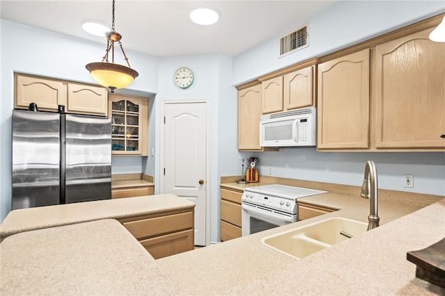 kitchen featuring white appliances, visible vents, light countertops, light brown cabinetry, and decorative light fixtures