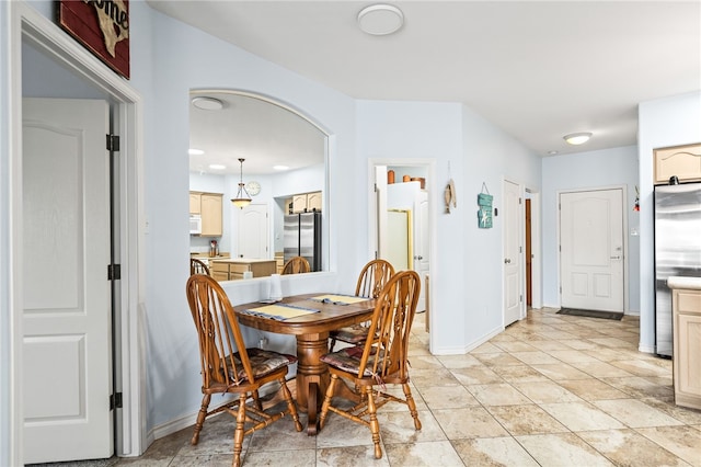 dining space with baseboards and arched walkways