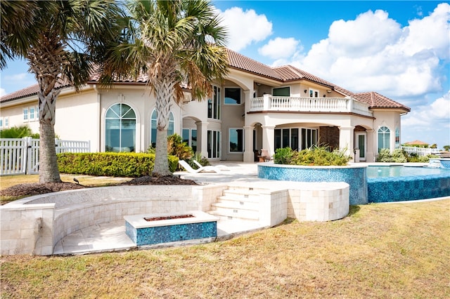 back of property featuring a pool with hot tub, a lawn, a balcony, and a patio area