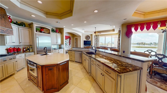 kitchen featuring a kitchen island with sink, sink, and a raised ceiling