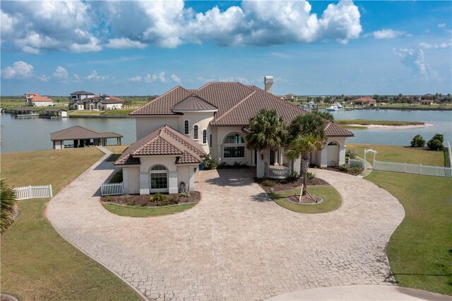 153 E Tuscany Way, Port Oconnor, TX 77982 - mediterranean / spanish home with curved driveway, a water view, stucco siding, and a tiled roof