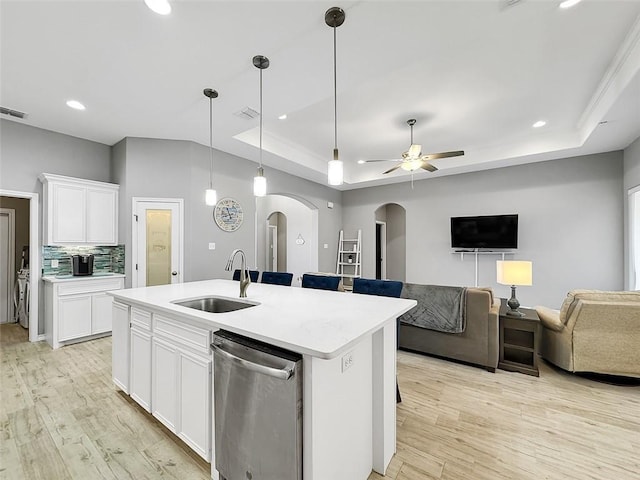 kitchen featuring sink, dishwasher, a kitchen island with sink, white cabinets, and a raised ceiling