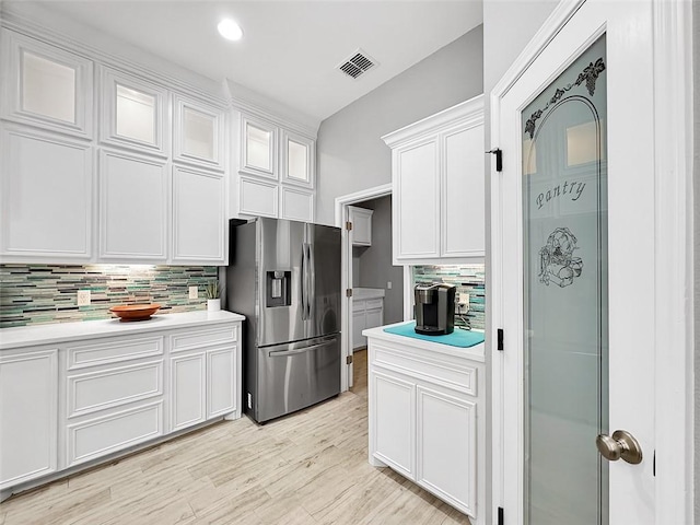 kitchen featuring tasteful backsplash, stainless steel fridge with ice dispenser, and white cabinets