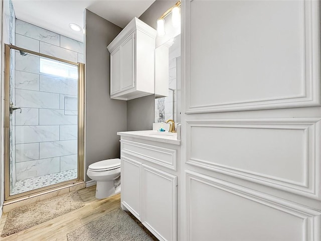 bathroom with vanity, toilet, hardwood / wood-style floors, and walk in shower