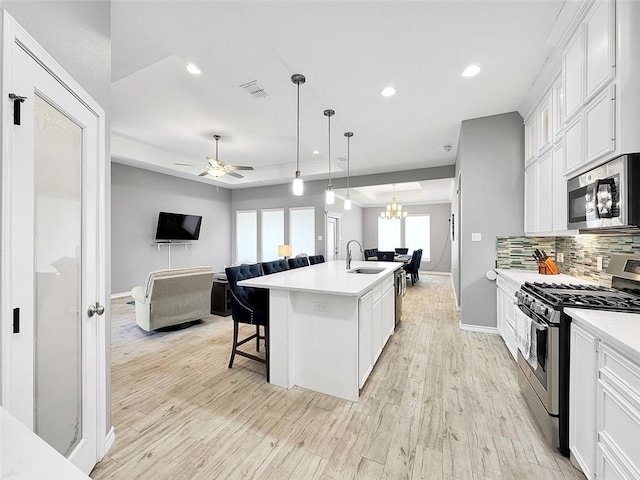 kitchen featuring sink, white cabinets, a kitchen bar, a kitchen island with sink, and stainless steel appliances