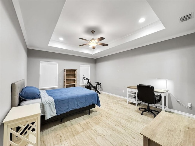 bedroom with ornamental molding, light hardwood / wood-style floors, ceiling fan, and a tray ceiling