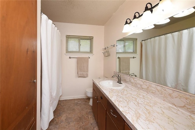 bathroom featuring vanity, a healthy amount of sunlight, toilet, and a textured ceiling