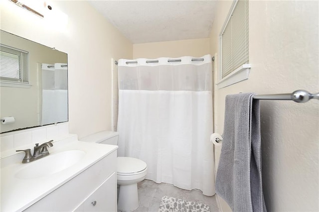 bathroom featuring a textured ceiling, vanity, and toilet