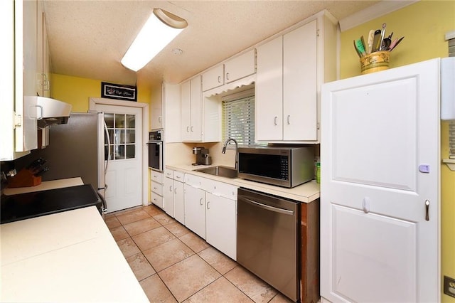 kitchen with white cabinets, light tile patterned flooring, sink, and stainless steel appliances