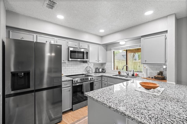 3029 White Bird Dr, Corpus Christi, TX 78415 - kitchen featuring stainless steel appliances, gray cabinets, a sink, a textured ceiling, and light stone counters