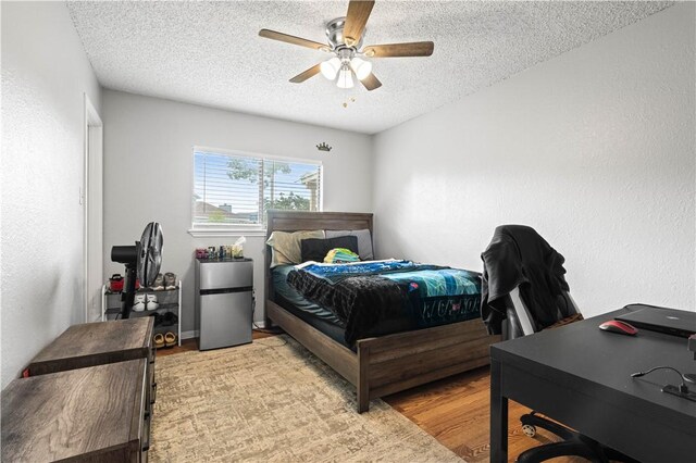3029 White Bird Dr, Corpus Christi, TX 78415 - bedroom with a textured ceiling, a desk, light wood-type flooring, a ceiling fan, and freestanding refrigerator