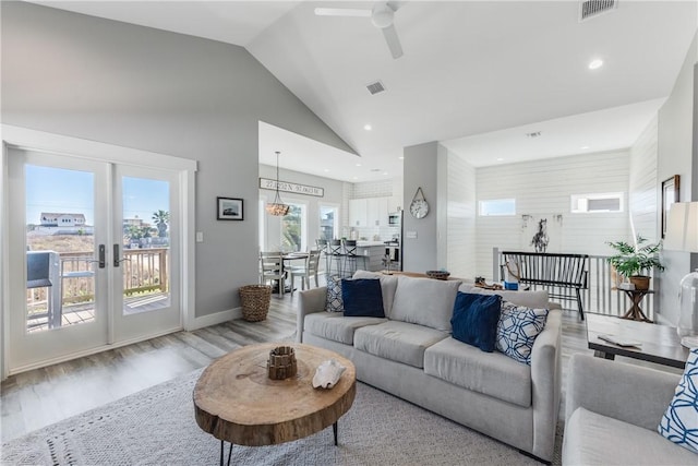 living room featuring light hardwood / wood-style floors, french doors, high vaulted ceiling, and ceiling fan