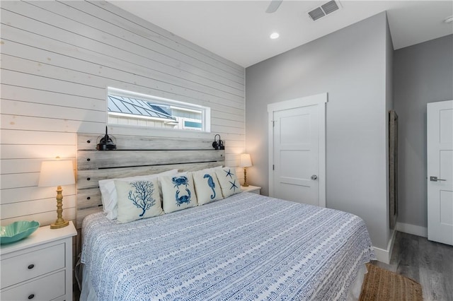 bedroom featuring ceiling fan, wood-type flooring, and wood walls