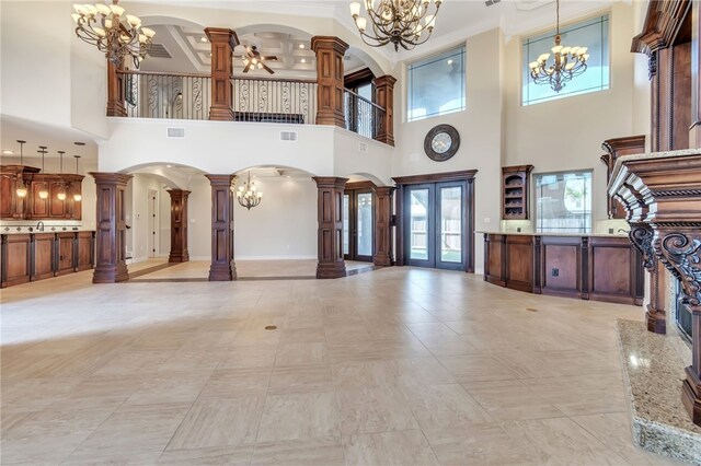 6522 Miranda Dr, Corpus Christi, TX 78414 - unfurnished living room with decorative columns, a chandelier, arched walkways, a towering ceiling, and ornamental molding