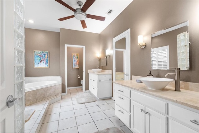 bathroom featuring vanity, tile patterned floors, a relaxing tiled tub, ceiling fan, and toilet