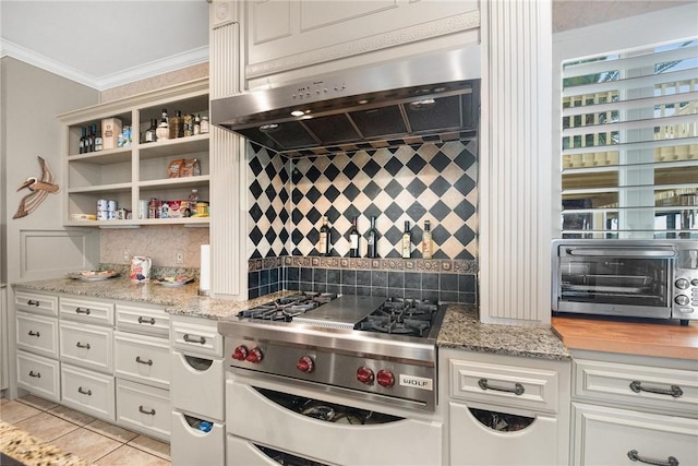 kitchen featuring light tile patterned floors, high end range, extractor fan, decorative backsplash, and white cabinets