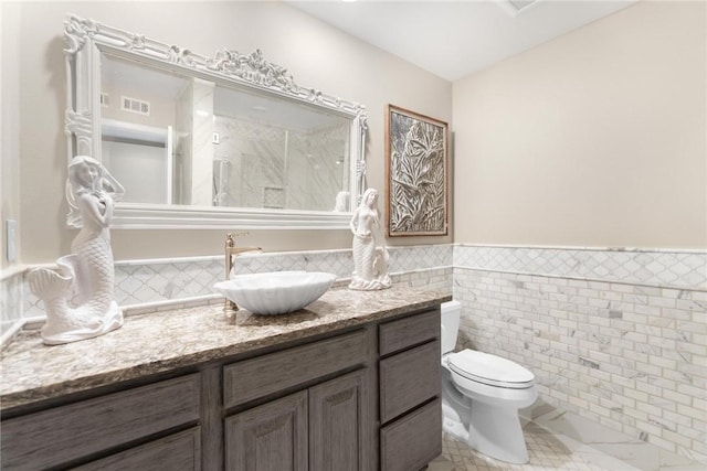 bathroom with vanity, toilet, and tile walls