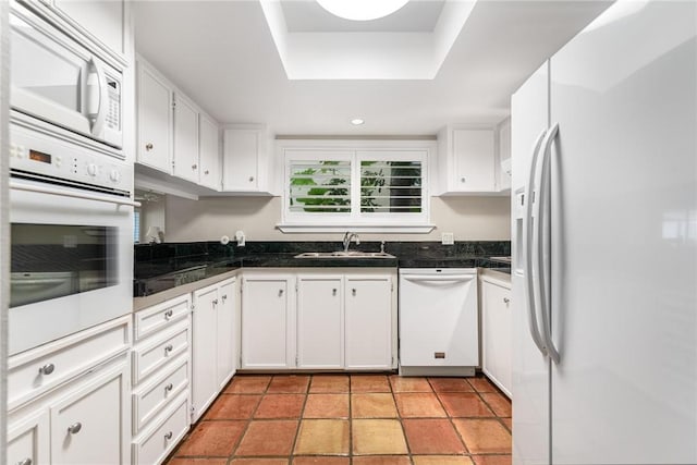 kitchen featuring a raised ceiling, white appliances, white cabinetry, and sink