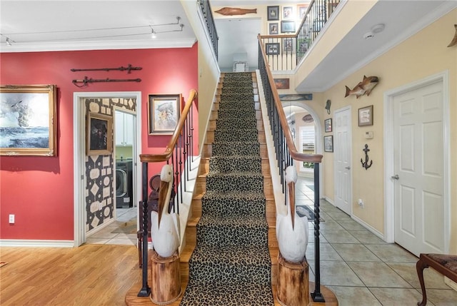 stairs with wood-type flooring, washer / clothes dryer, and ornamental molding