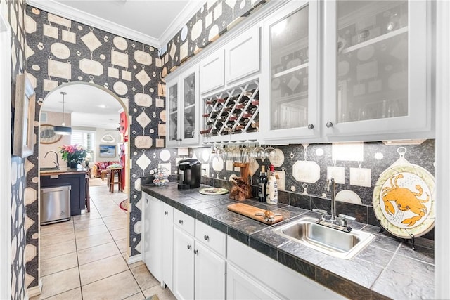 kitchen featuring white cabinets, light tile patterned floors, crown molding, and sink