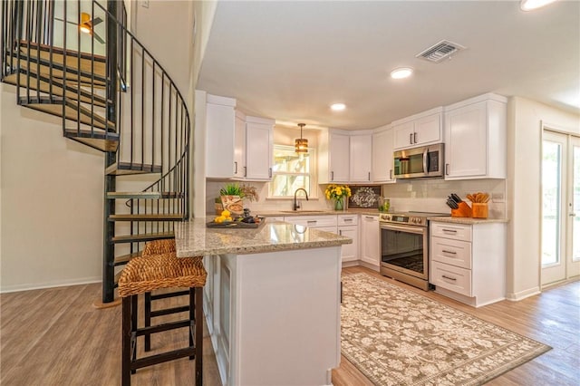 2322 Violet, Corpus Christi, TX 78410 - kitchen featuring appliances with stainless steel finishes, a sink, a peninsula, white cabinetry, and recessed lighting
