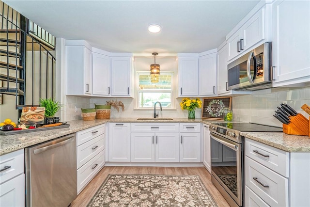 2322 Violet, Corpus Christi, TX 78410 - kitchen featuring appliances with stainless steel finishes, a sink, white cabinets, light wood finished floors, and recessed lighting