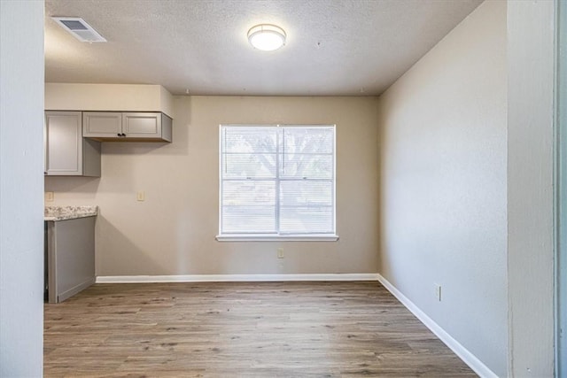 4113 Sierra St, Corpus Christi, TX 78410 - unfurnished dining area with light wood-style flooring, baseboards, and a textured ceiling