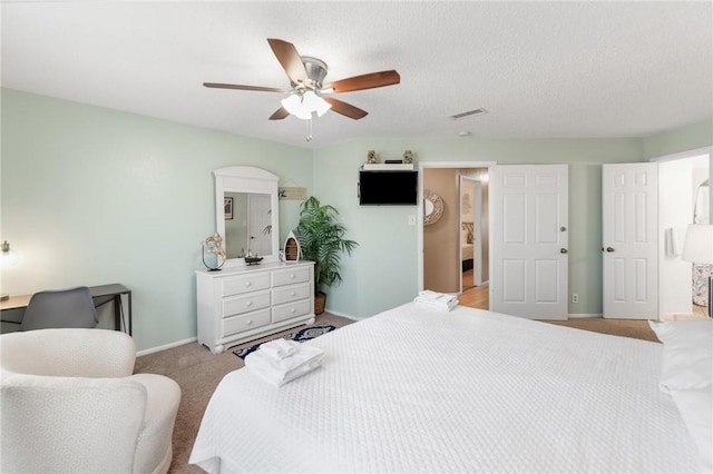 bedroom with ceiling fan, light colored carpet, and a textured ceiling