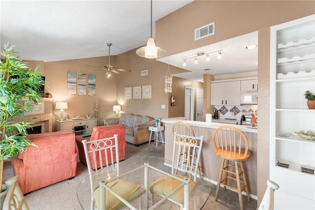 dining space featuring vaulted ceiling, sink, light colored carpet, ceiling fan, and a textured ceiling