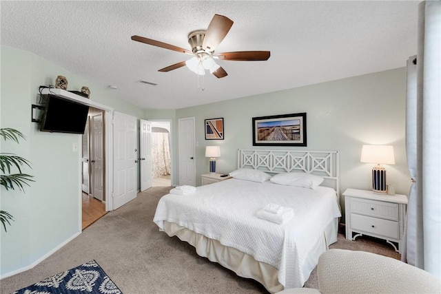 carpeted bedroom with ceiling fan, connected bathroom, and a textured ceiling