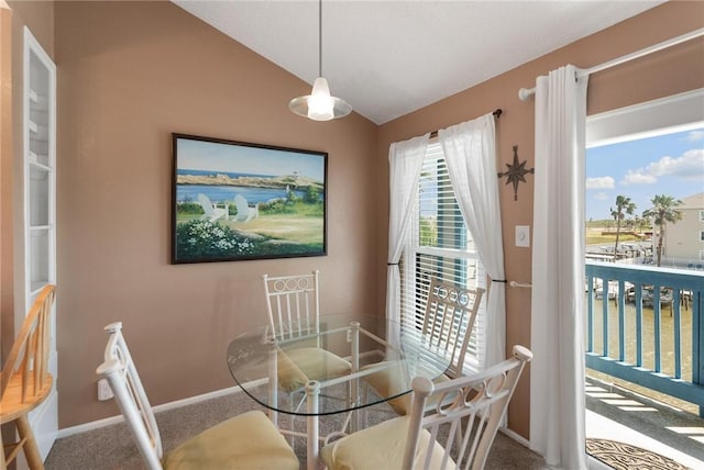 carpeted dining space with a water view and lofted ceiling