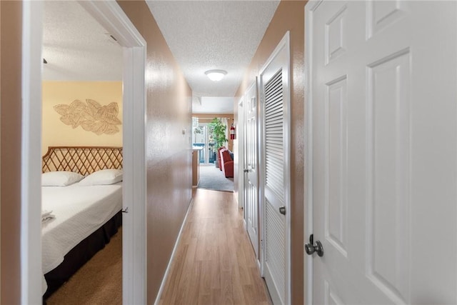 hall with light hardwood / wood-style floors and a textured ceiling